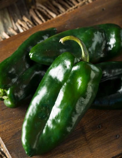 Green jalapeno peppers on a wooden cutting board.
